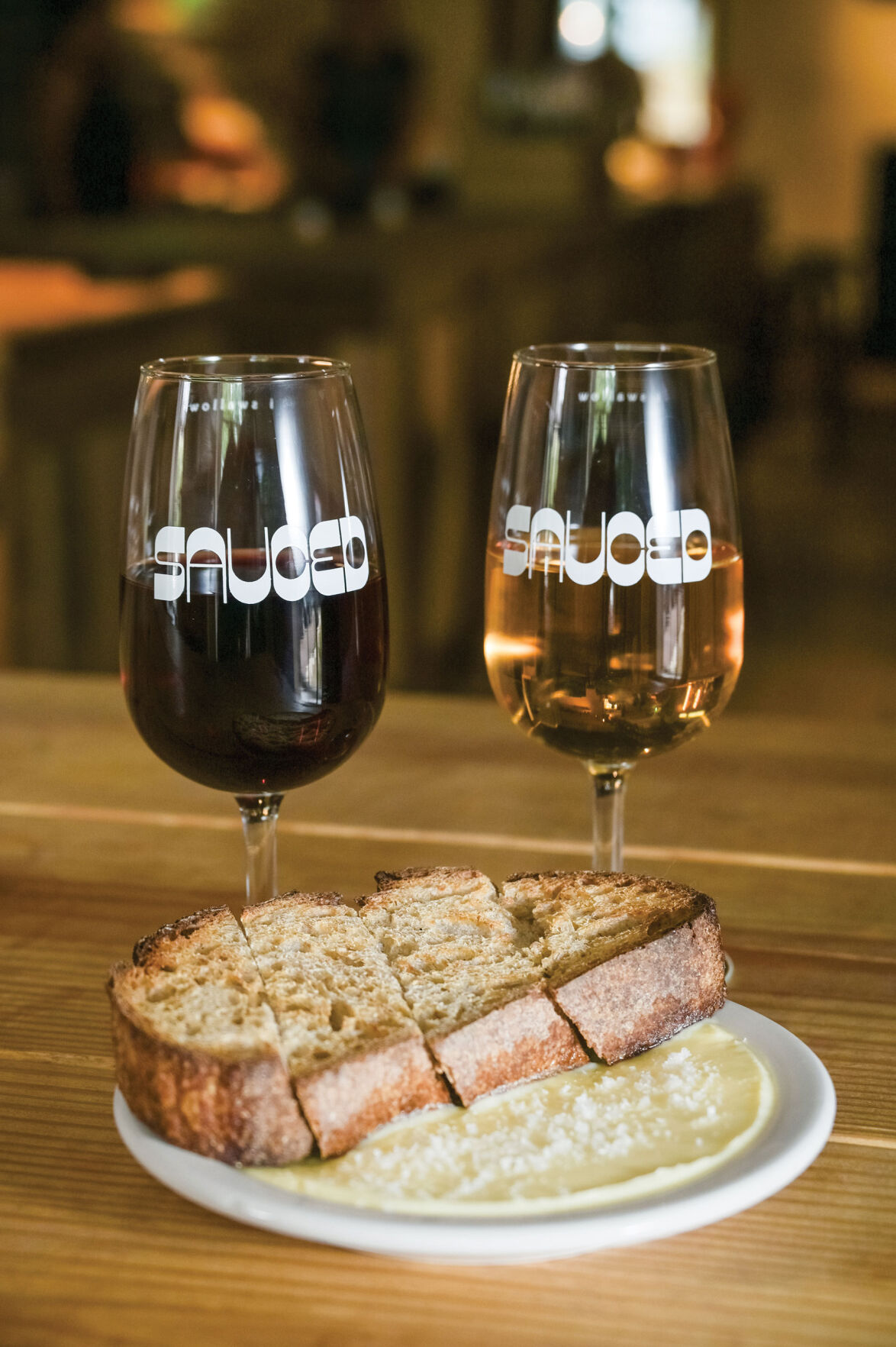 Bread and butter on a plate in front of two wine glasses
